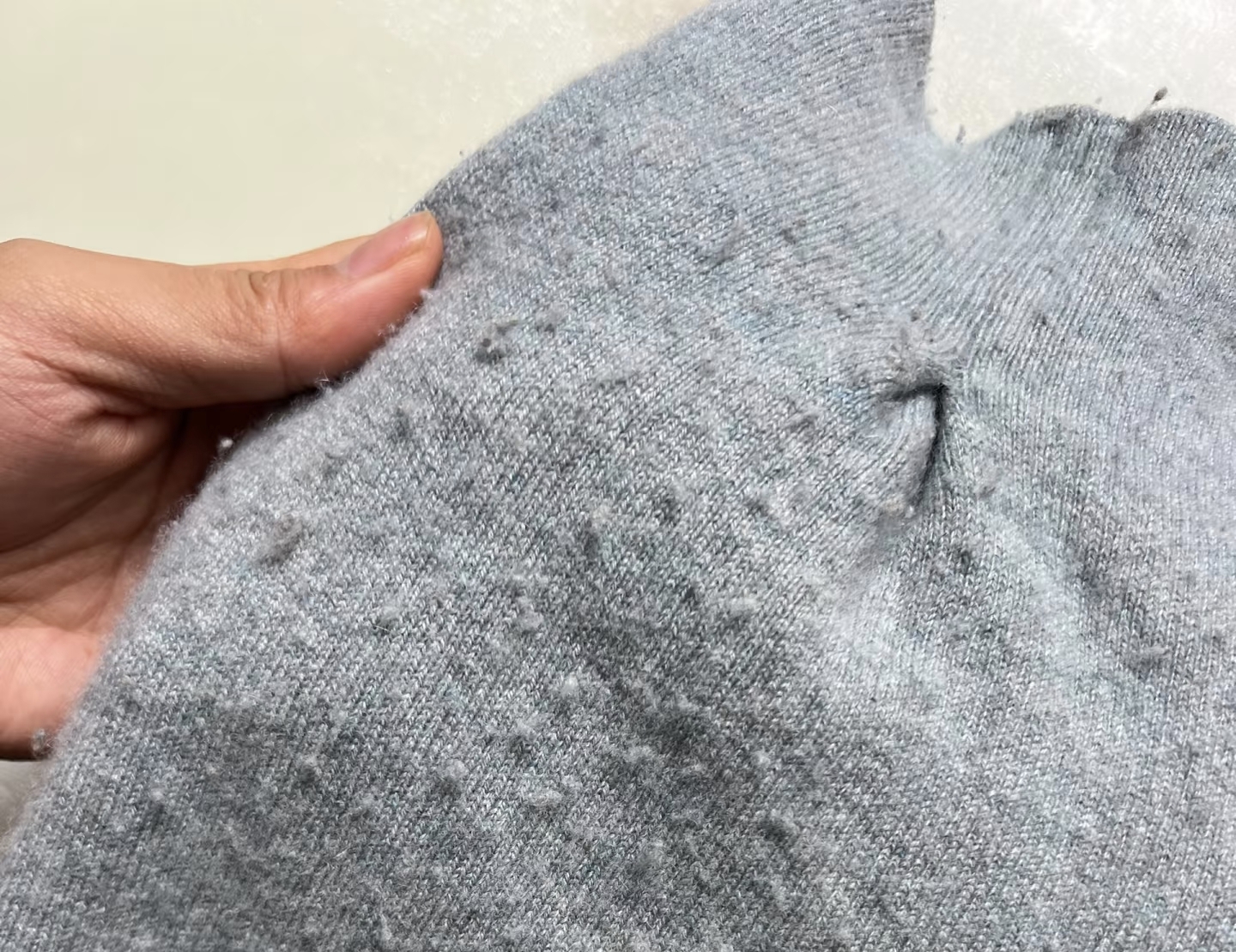 A sweater that has formed balls of yarn on its surface.